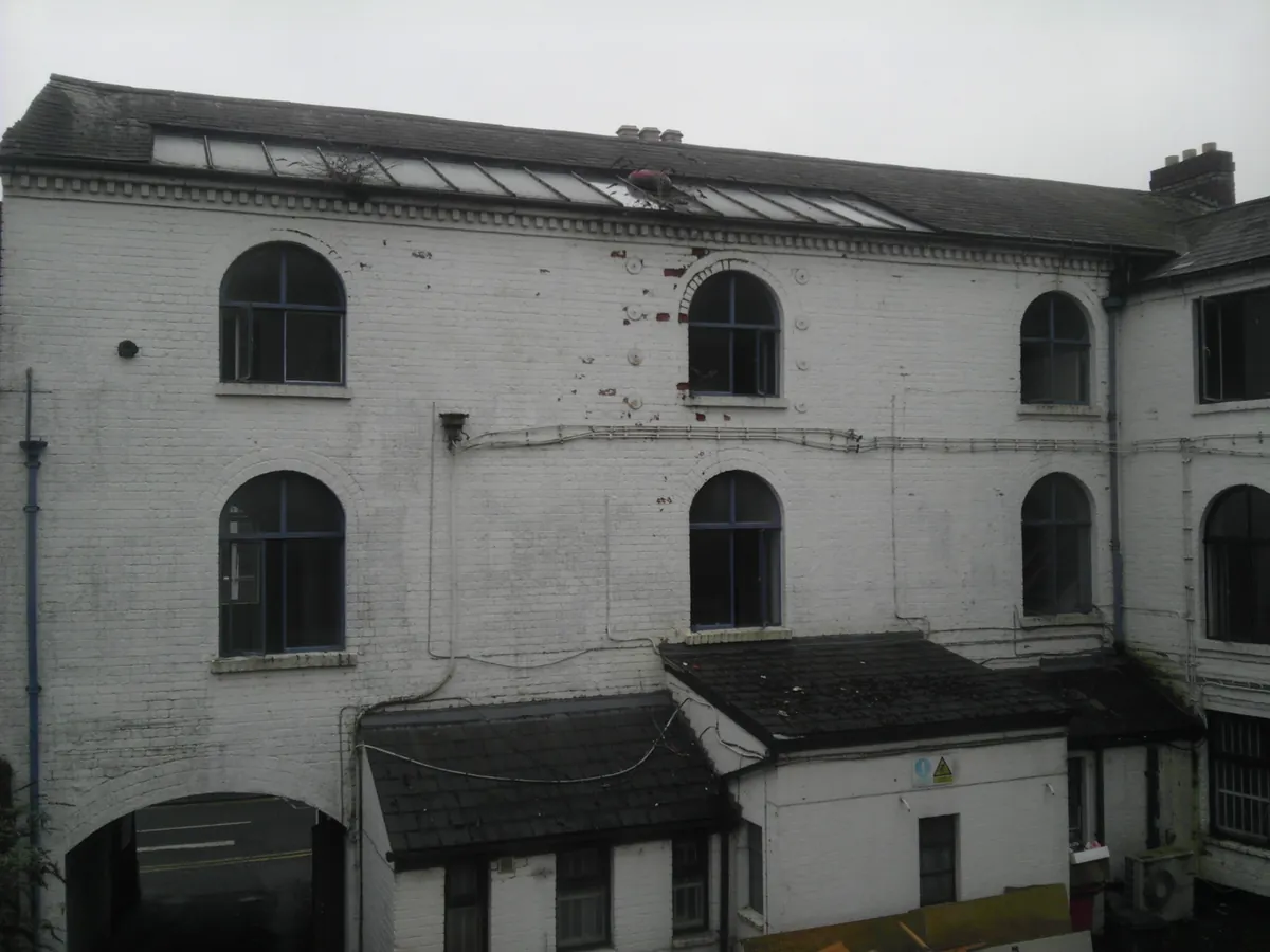 Rear elevation of a white painted mixed-use building with arched windows